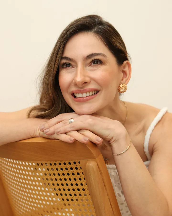 Dra. Tainá Fracaroli sorrindo, apoiada no encosto de uma poltrona